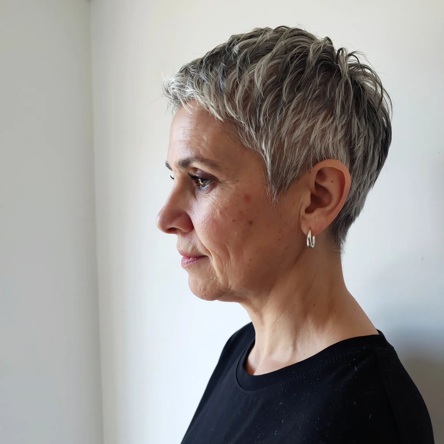 Pixie argent poudré femme 61 ans, coupe moderne et artistique dans une galerie lumineuse.