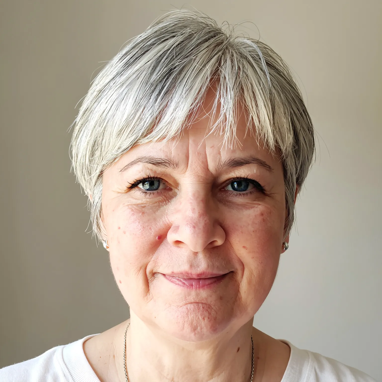 Pixie gris en multiples couches femme 62 ans, coupe courte douce et volumineuse au style naturel.