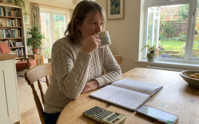 Personne organisant son budget personnel à la maison avec un carnet et une calculatrice pour mieux gérer ses finances mensuelles.