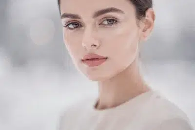 Routine December Skin Reset mise en scène, femme au teint lumineux en lumière douce hivernale, ambiance beauté minimaliste