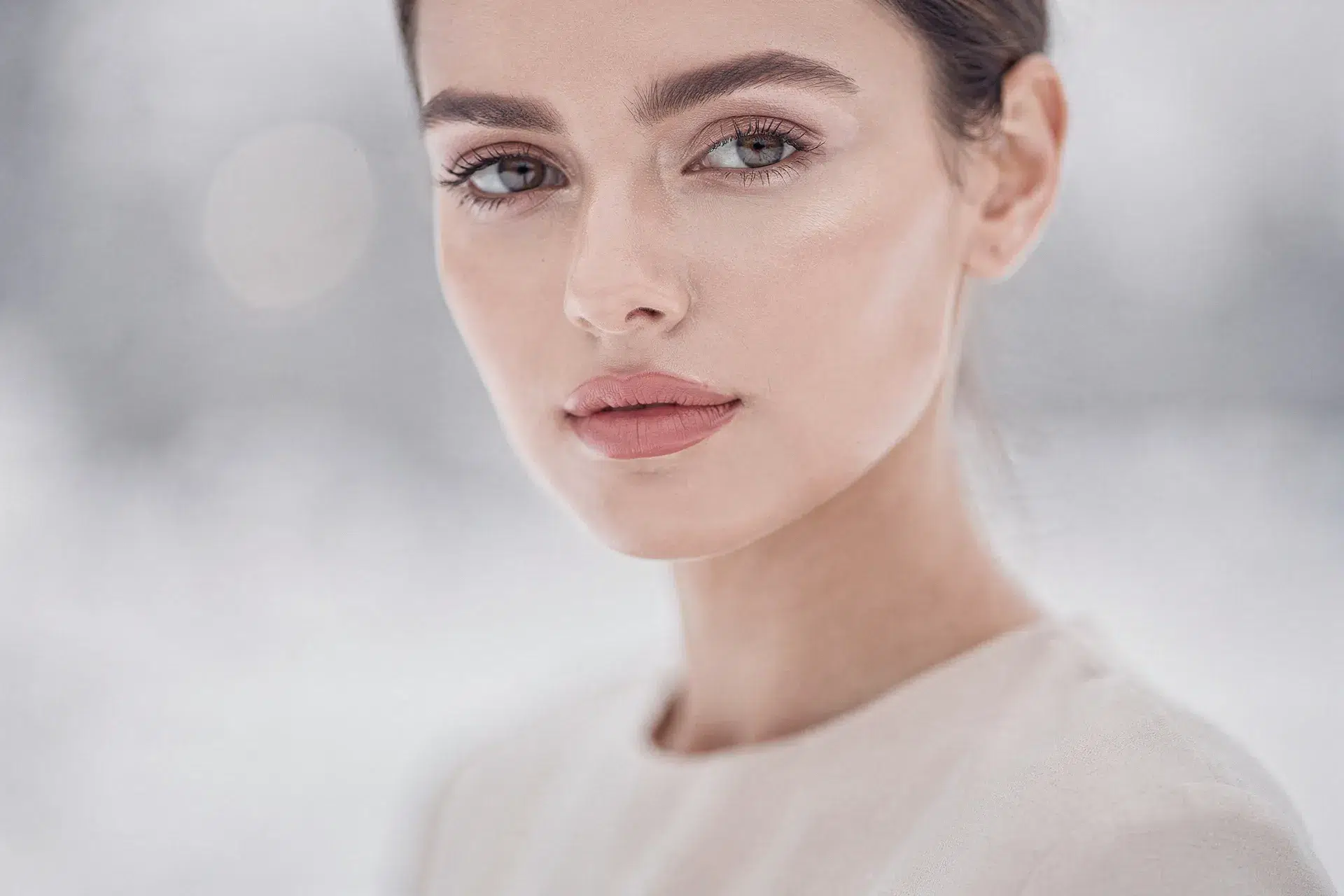 Routine December Skin Reset mise en scène, femme au teint lumineux en lumière douce hivernale, ambiance beauté minimaliste