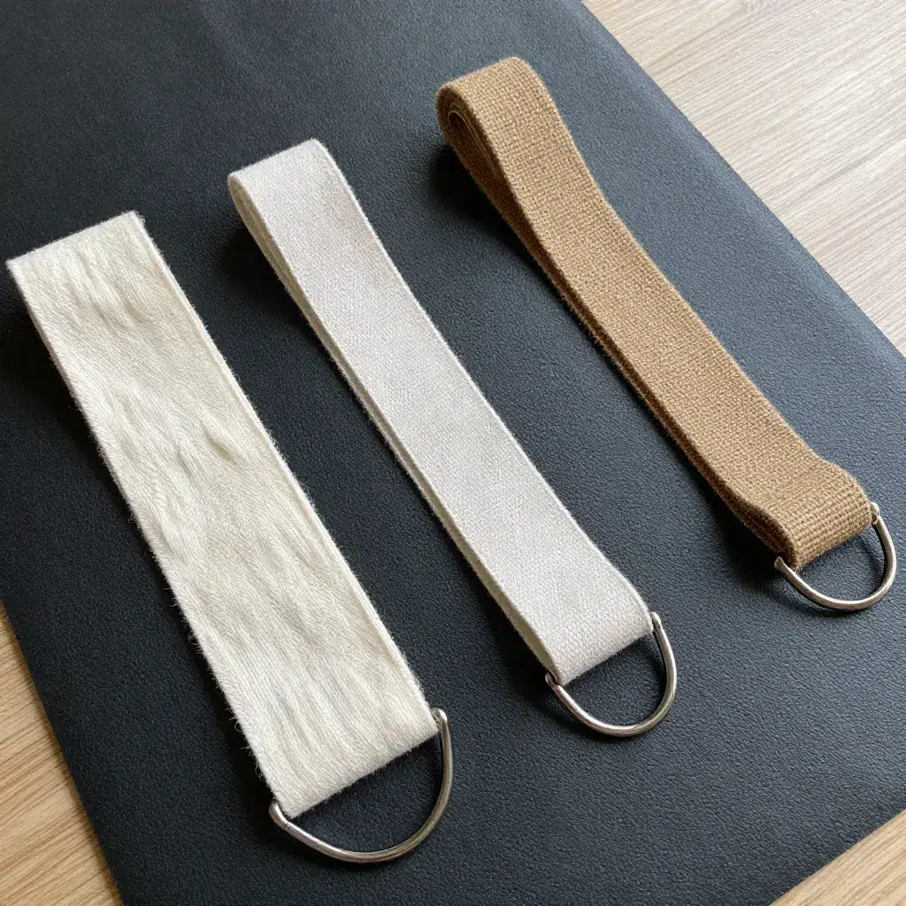 Trois sangles de yoga différentes coton bio nylon chanvre avec boucles métalliques sur tapis