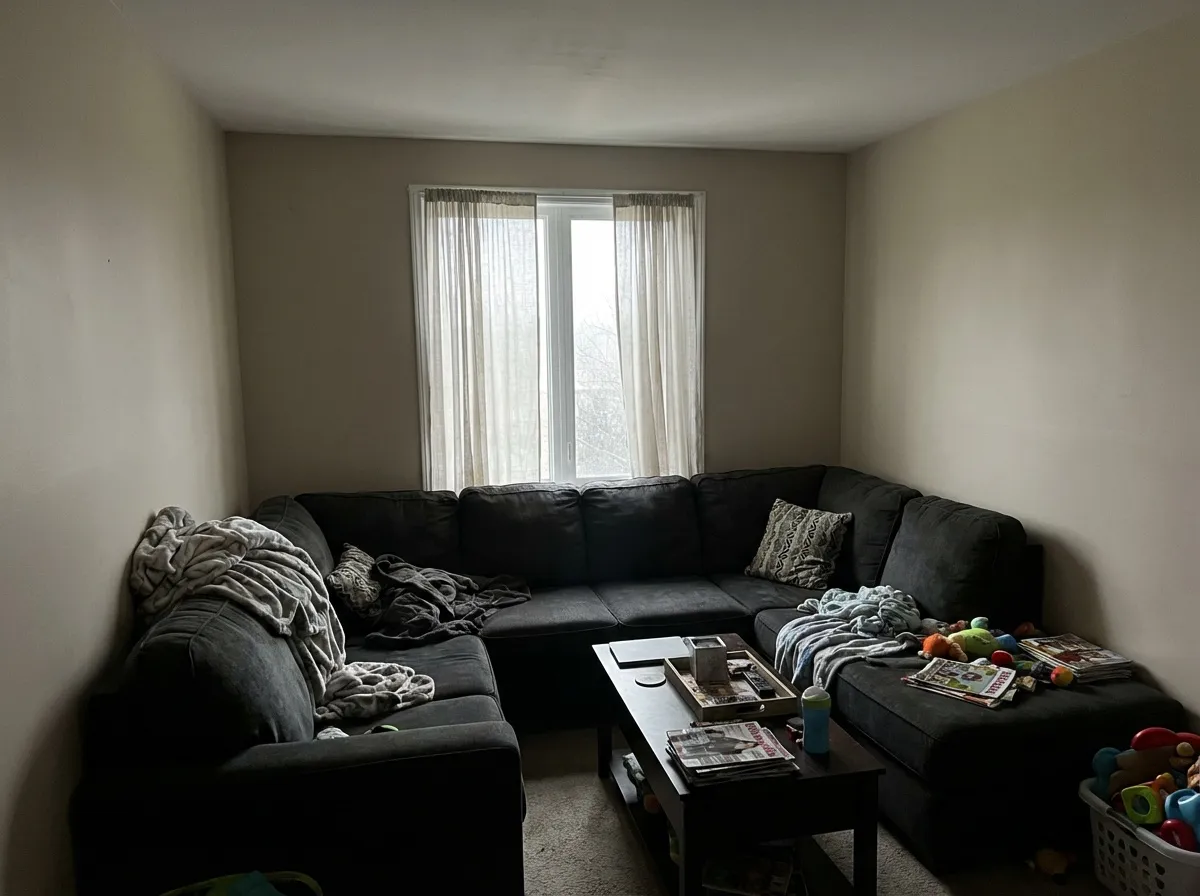 Erreur classique d'agencement : grand canapé d'angle sombre plaqué contre deux murs dans un petit salon, bloquant la circulation et la lumière naturelle