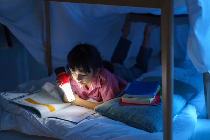 Un enfant lit son journal quotidien sous sa couverture - abonnement presse enfant