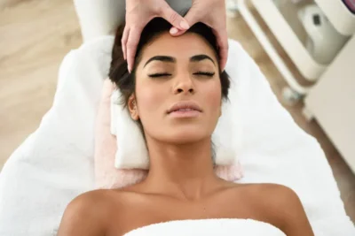 Femme recevant un massage crânien relaxant dans un head spa, mains du praticien sur le front pour soulager les tensions et stimuler la circulation.