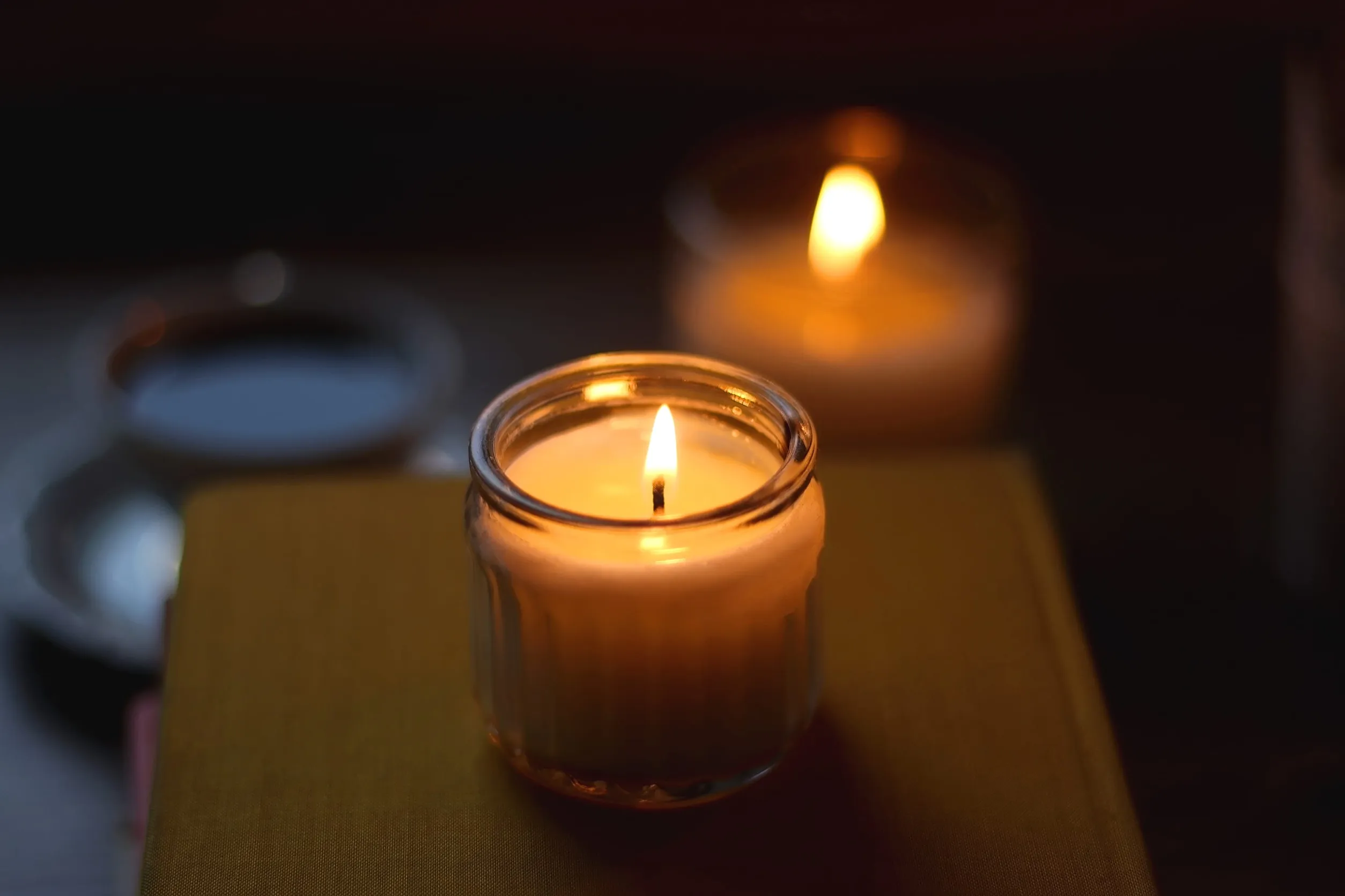Deux bougies allumées dans des photophores en verre posés sur un livre pour une ambiance tamisée.