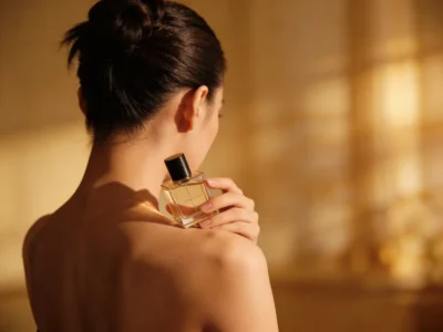 Femme tenant un flacon de parfum dans une lumière dorée, incarnant l'idée de construire sa propre signature olfactive au quotidien.