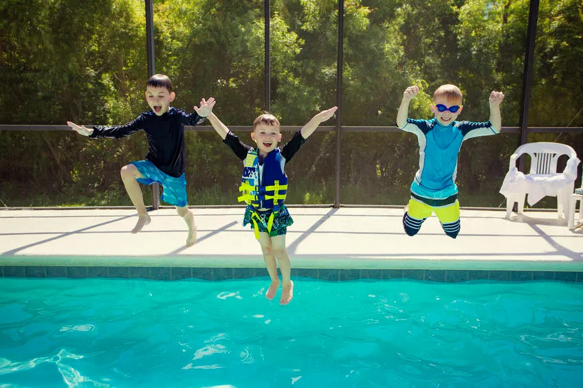 Enfants qui jouent et sautent à la piscine avec de bonnes tenues de bain garcon