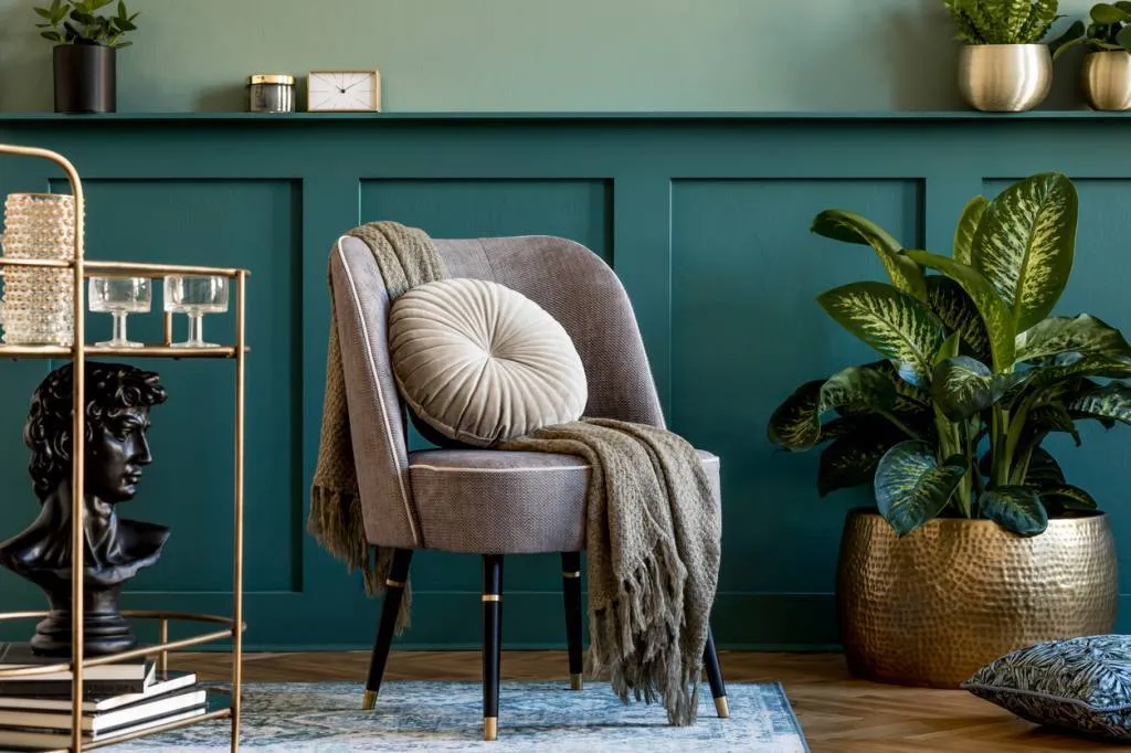 Fauteuil scandinave gris avec coussin rond sur fond de mur à moulures vert canard.