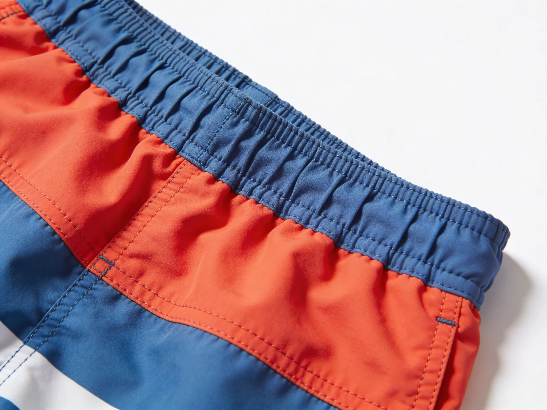 Gros plan sur l'élastique et les coutures renforcées d'un short de bain garçon, détail tissu technique résistant
