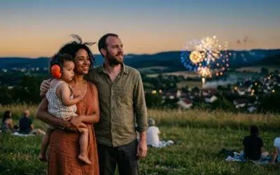 feu-artifice-bebe-famille-distance Famille regardant un feu d'artifice à distance le soir, tout-petit portant un casque anti-bruit