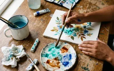 materiel-aquarelle-cover Mains d'une femme peignant à l'aquarelle sur papier coton avec palette et pinceau rond