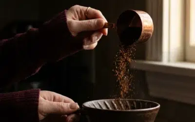 Mains versant du café moulu de spécialité dans un dripper en céramique noire, lumière contrastée